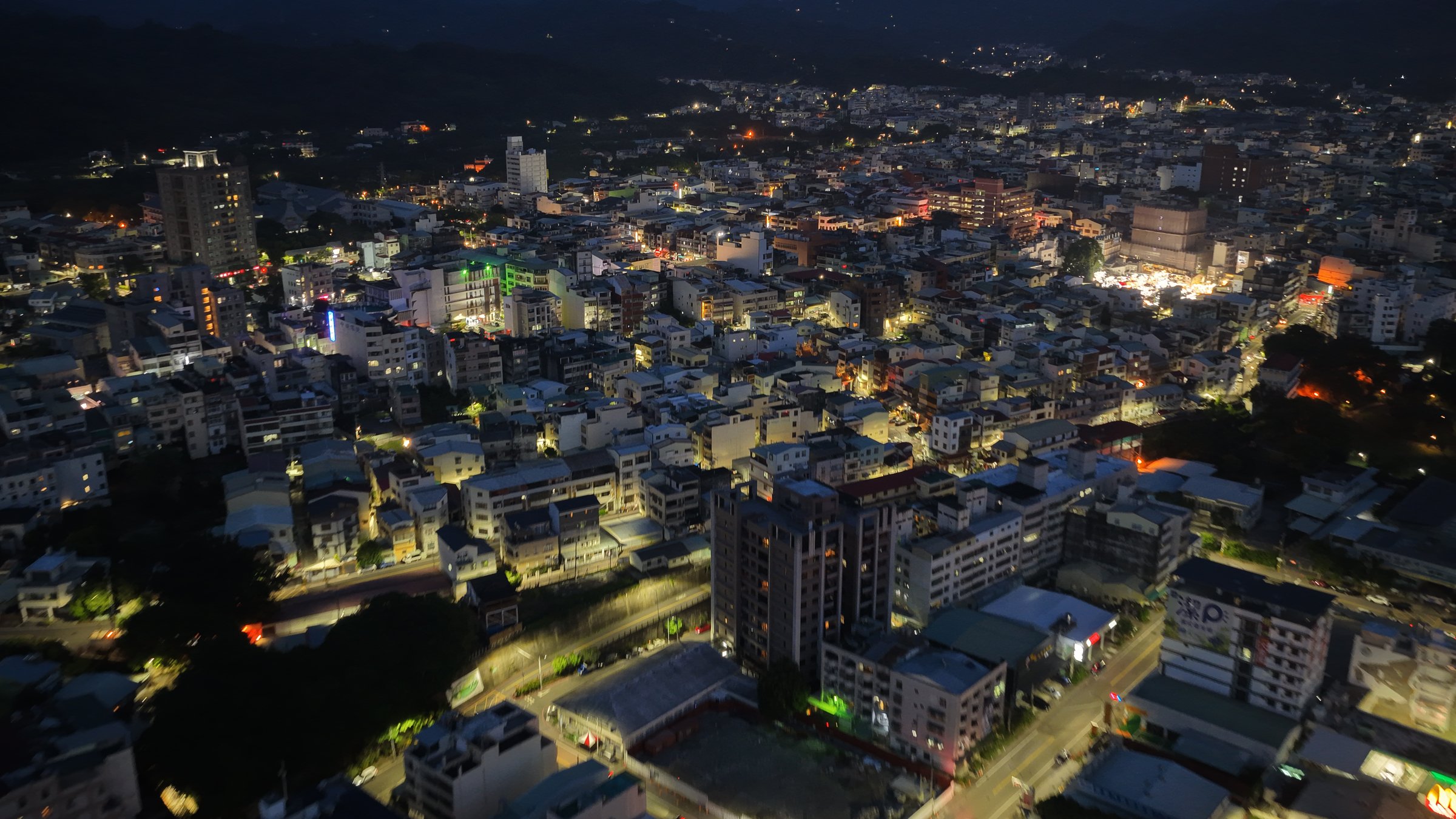 夜間空拍俯瞰畫面，市鎮燈火密集分佈，浮水印示意疊於畫面之上。